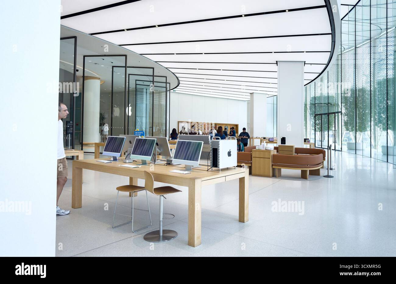 Moderno interno del negozio Apple nel Dubai Mall negli Emirati Arabi Uniti, con design elegante, clienti che sfogliano prodotti tecnologici e una serie di computer iMac in esposizione - Immagine stock catturata con smartphone
