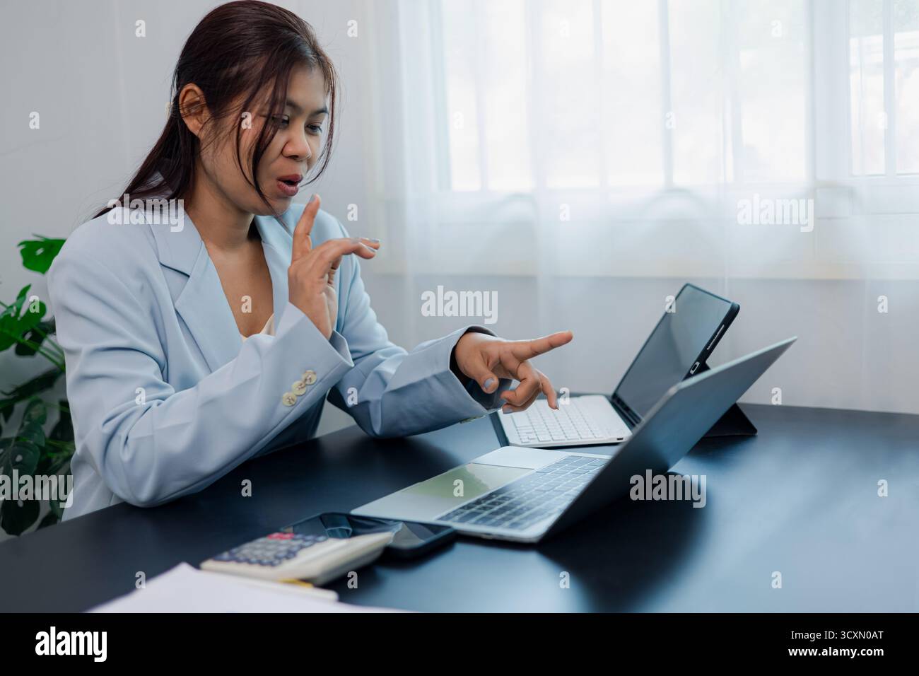 Donna d'affari che parla e punta sullo schermo del notebook durante le videoriunioni online, concetto di comunicazione digitale, lavoro di squadra e lavoro remoto in chiave moderna Foto Stock