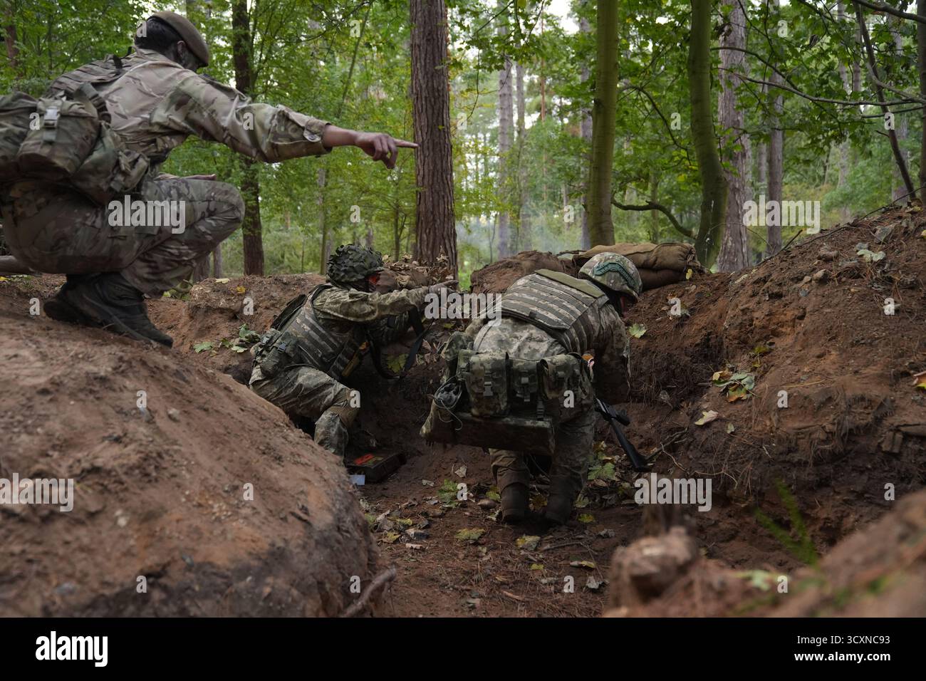 I soldati ucraini, che stanno ancora seguendo il loro corso di formazione per la leadership nell'ambito dell'operazione Interflex guidata dal Regno Unito, prendono parte all'addestramento di trincea condotto da membri delle guardie irlandesi in un campo di addestramento dell'esercito britannico nell'Inghilterra orientale. Data foto: Mercoledì 15 ottobre 2025. Foto Stock