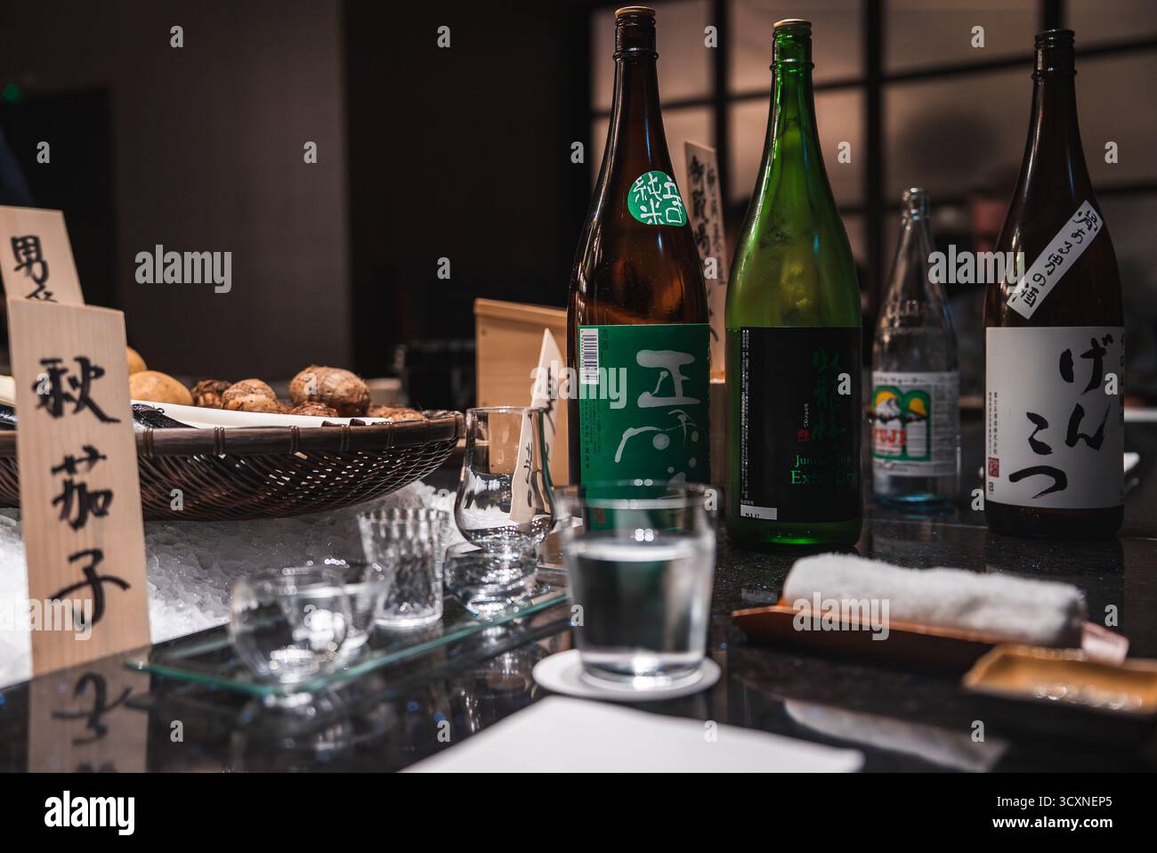 Bancone del bar dell'hotel con bottiglie di sake giapponesi e disposizione degustazione Foto Stock