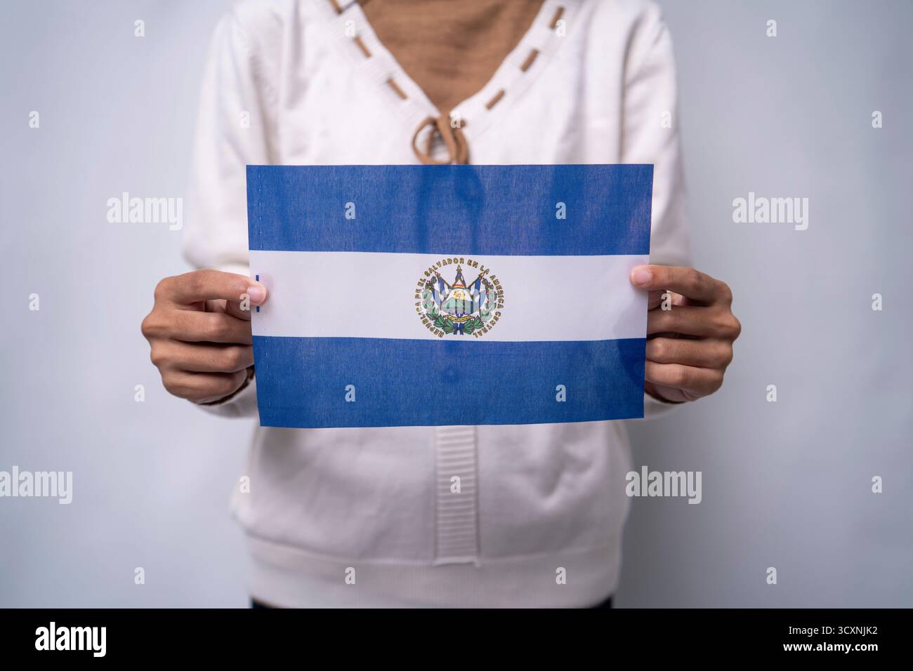 Persona che detiene la bandiera di El Salvador con orgoglio Foto Stock