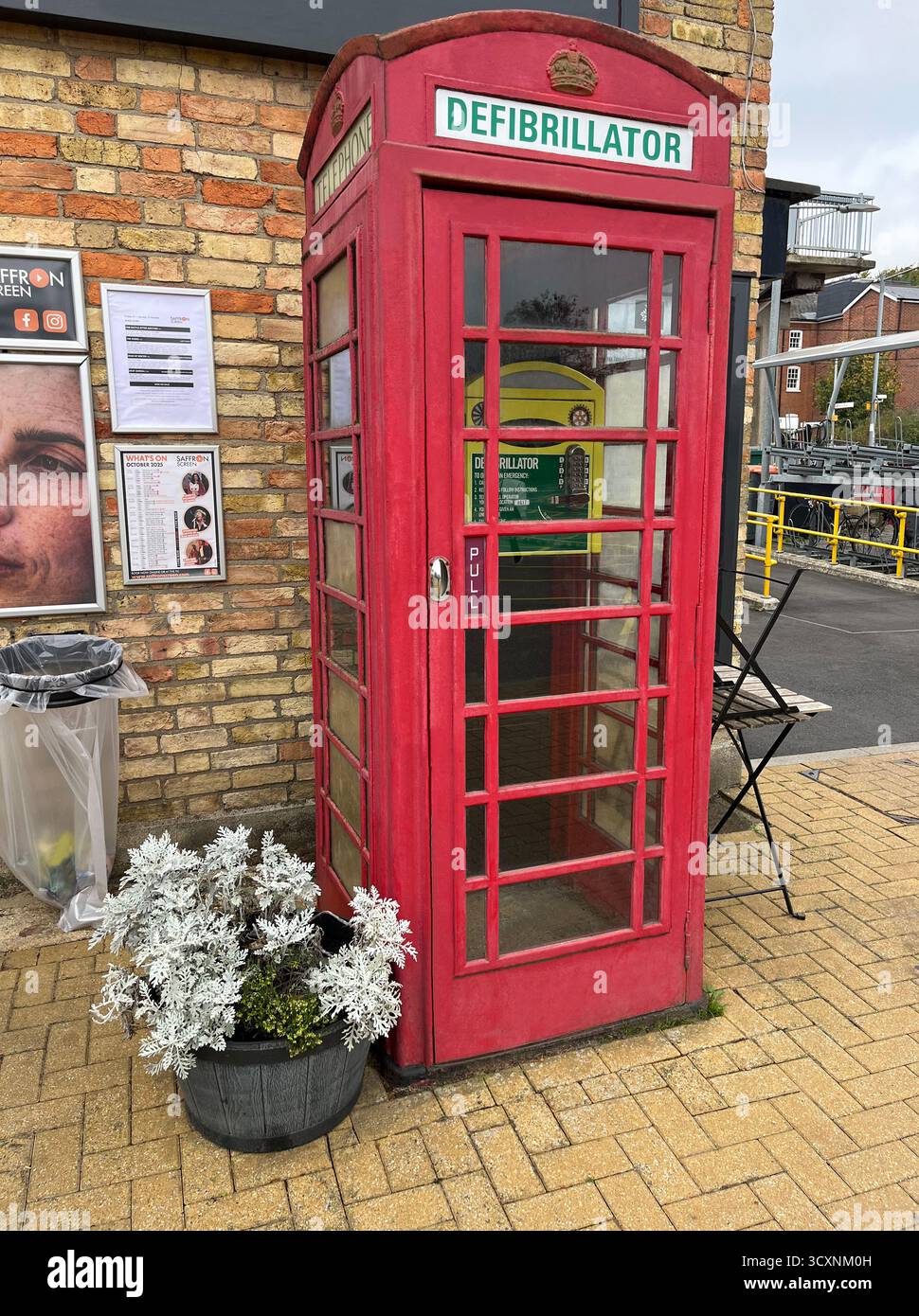Una cabina telefonica rossa destinata ad alloggiare un defibrillatore presso la stazione ferroviaria di Audley End, la stazione di Audley End, Station Road vicino a Saffron Walden, Essex C. Foto Stock