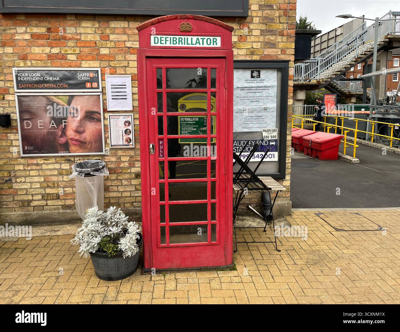 Una cabina telefonica rossa destinata ad alloggiare un defibrillatore presso la stazione ferroviaria di Audley End, la stazione di Audley End, Station Road vicino a Saffron Walden, Essex C. Foto Stock