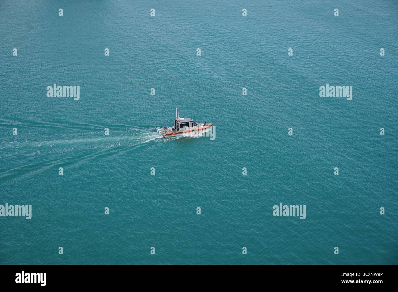 Una nave della Guardia Costiera statunitense viaggia attraverso le acque turchesi al largo di Port Canaveral, sottolineando la sicurezza e le operazioni marittime lungo la costa della Florida Foto Stock