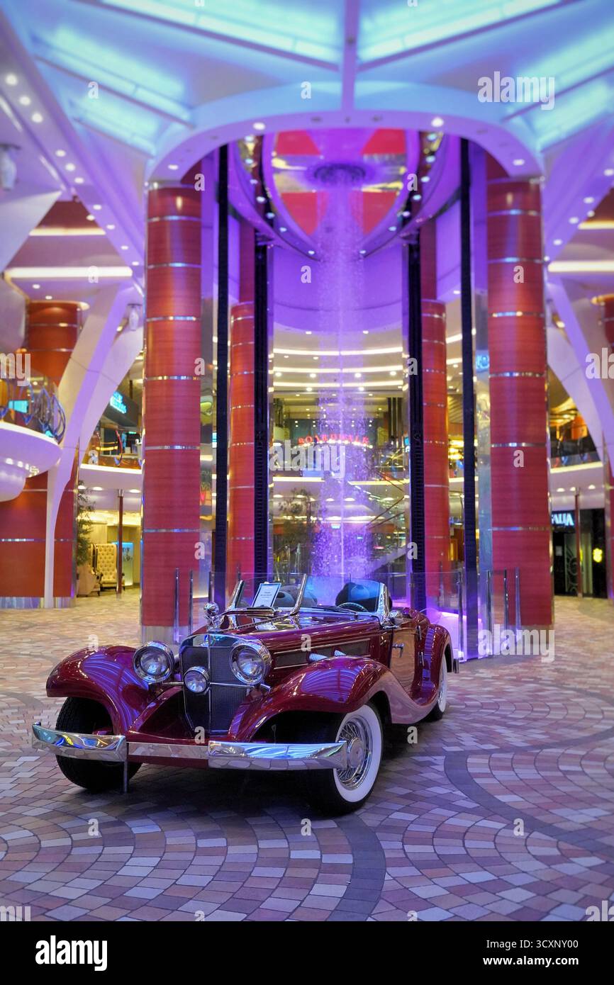 Una Mercedes-Benz Cabriolet d'epoca posizionata sotto la cascata di luce viola a bordo dell'Allure of the Seas dei Caraibi reali Foto Stock