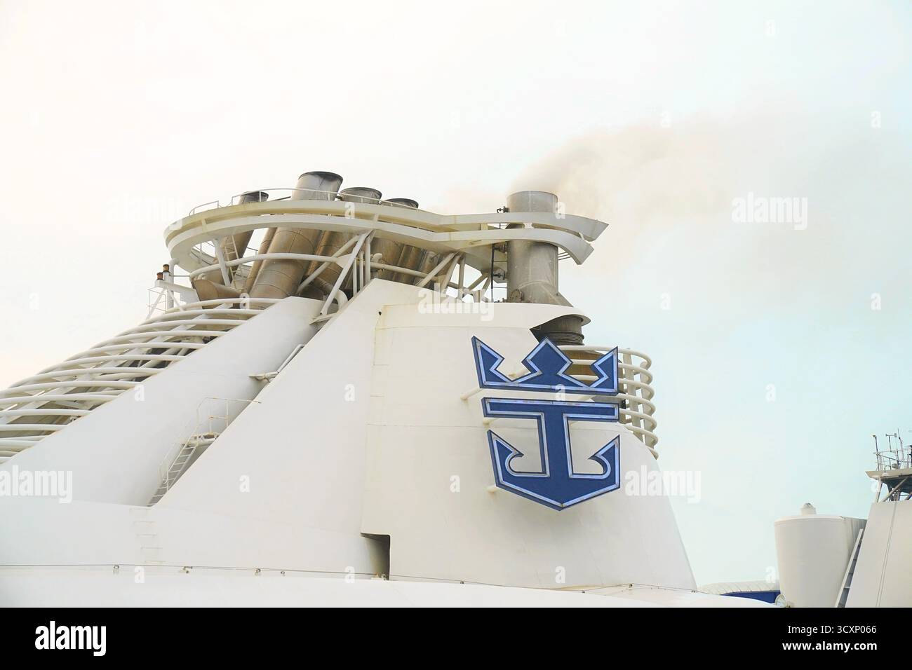 Una vista ravvicinata del logo Royal Caribbean e delle pile di scarico a bordo della Liberty of the Seas cattura i dettagli ingegneristici della nave contro un cielo nuvoloso Foto Stock