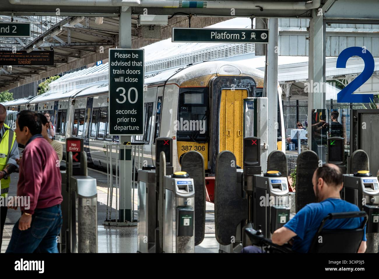 Treno al binario della stazione ferroviaria del Regno Unito con biglietteria e cartello di imbarco Foto Stock