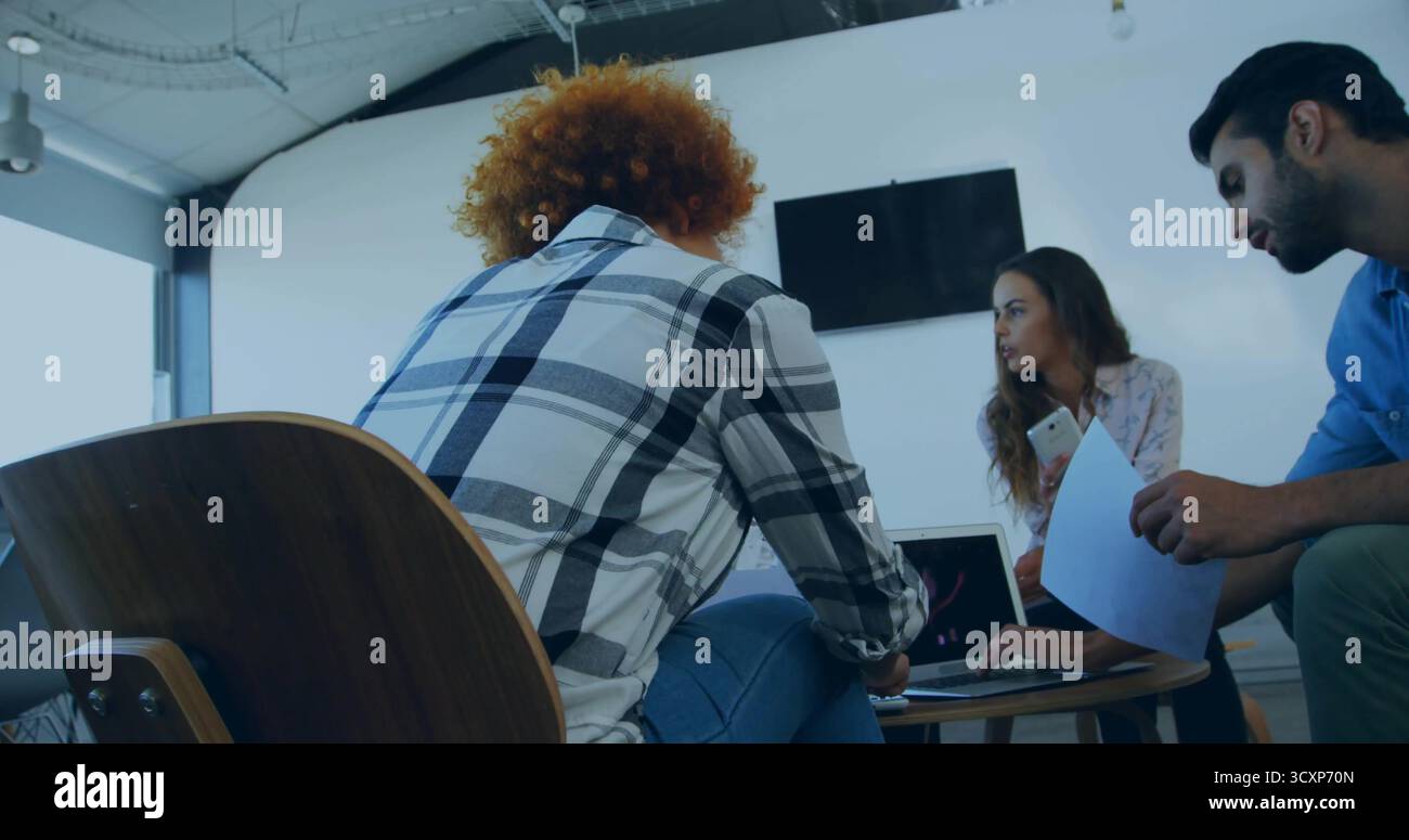 Brainstorming di colleghi che discutono di progetti su un tavolo di legno in ufficio, con un computer portatile e un documento Foto Stock