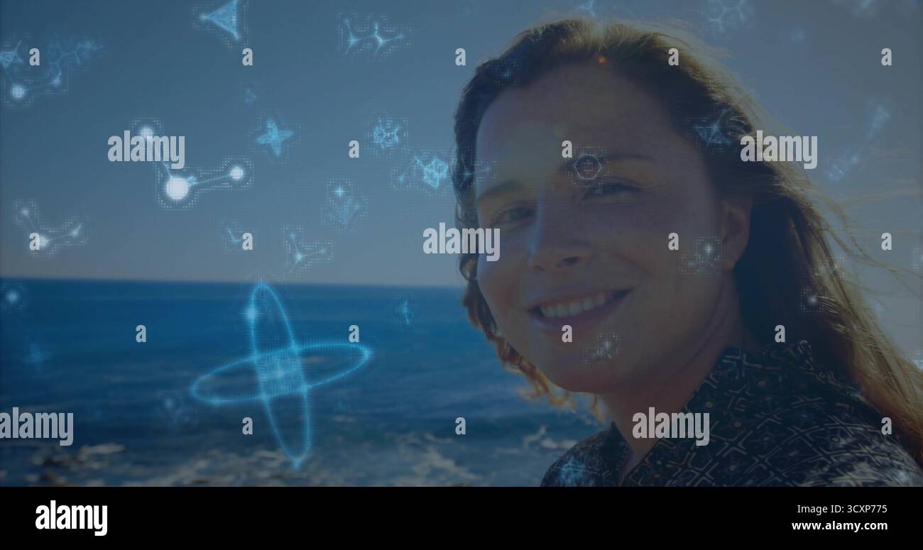 Donna sorridente che indossa una camicia scura in piedi accanto al mare, con ologrammi molecolari brillanti, spazio copia Foto Stock