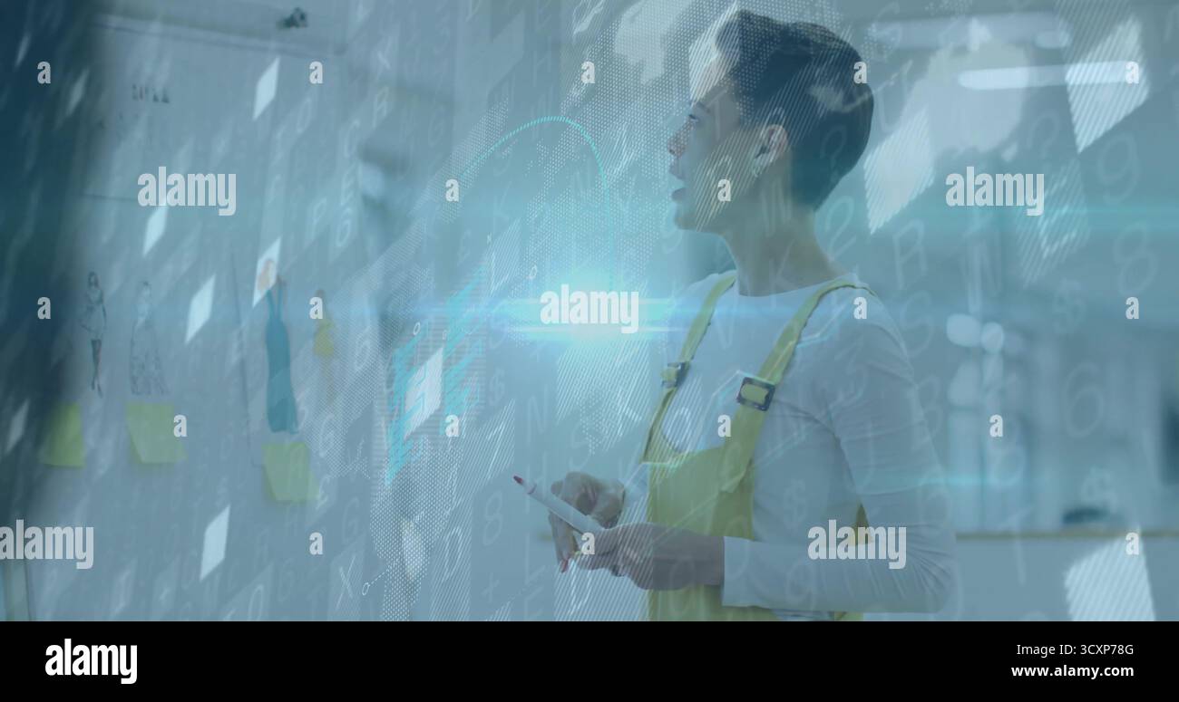 Analisi di una donna in tuta gialla con un tablet che esamina le foto su una parete di vetro in ufficio, copia spazio Foto Stock