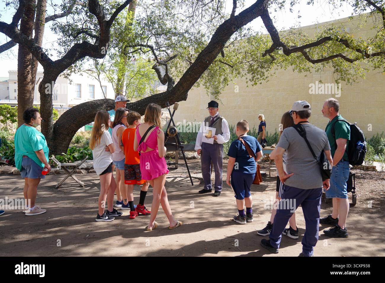 Un reenattore storico maschile parla a un gruppo di visitatori durante un programma educativo di storia vivente presso la missione di Alamo Foto Stock