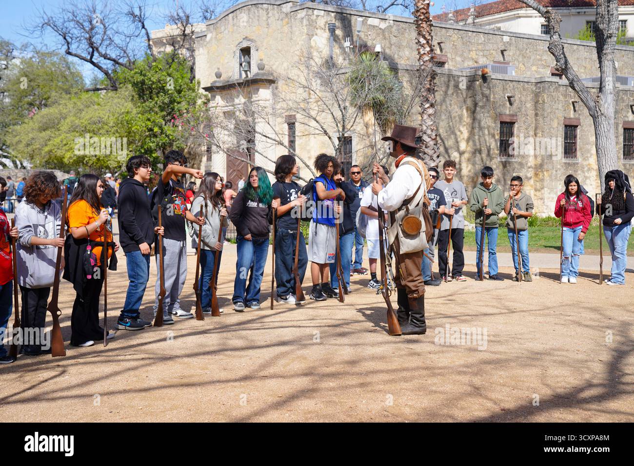 San Antonio, Texas, Stati Uniti d'America – 8 marzo 2024: Un reattore storico maschile istruisce un gruppo di studenti che tengono in mano moschetti replica durante un programma educativo Foto Stock