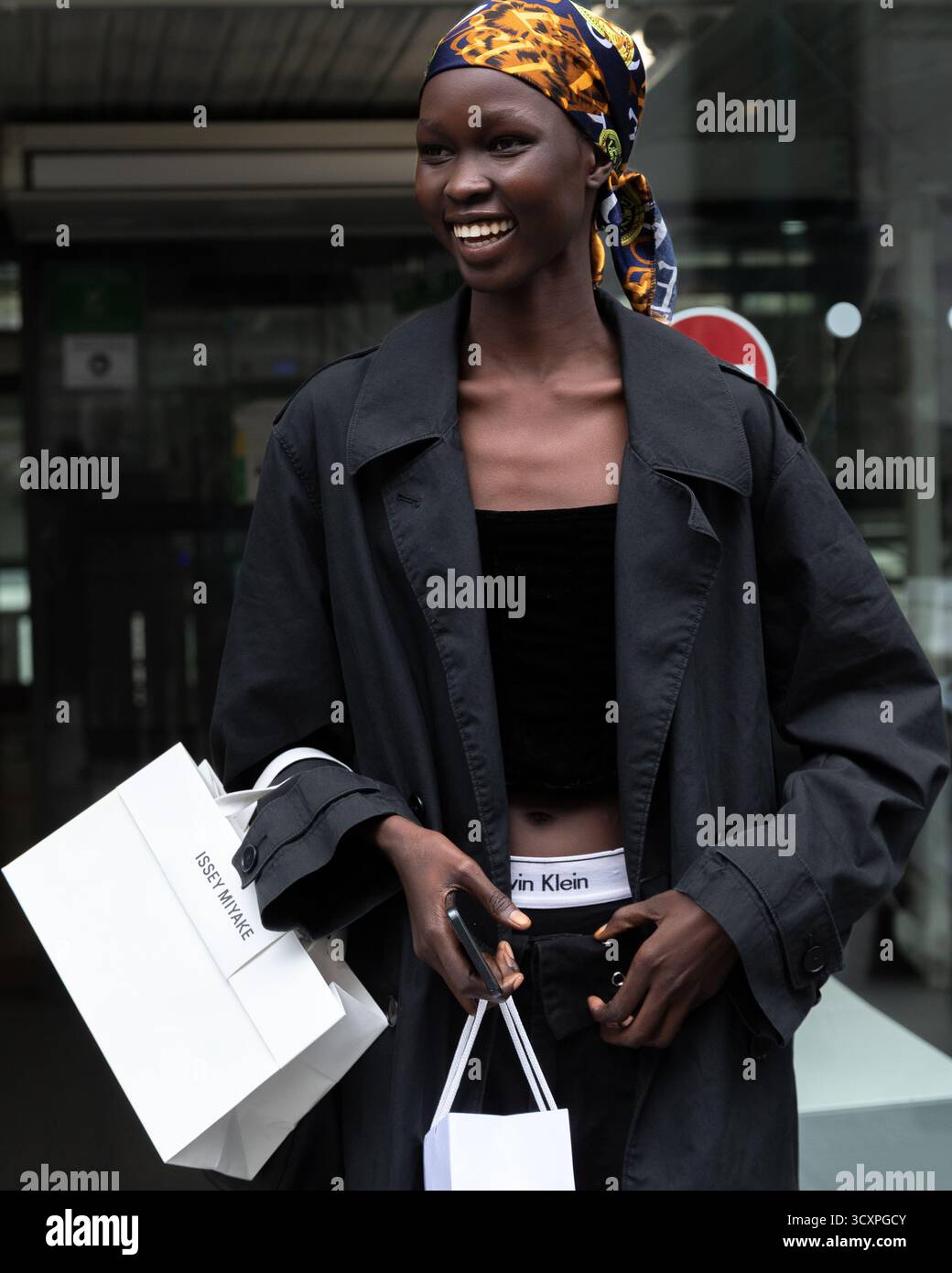 Un ospite che indossa un top nero, un cappotto nero e una bandana stampata arriva alla mostra Primavera/Estate 2026 di Issey Miyake durante la settimana della moda di Parigi. Foto Stock