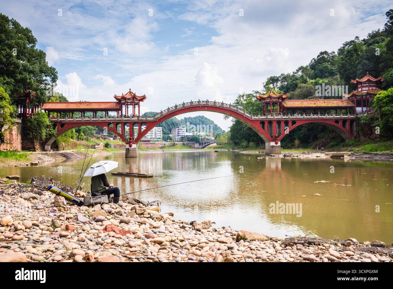 Leshan, Cina - 29 settembre 2018: Uomo che pesca sul fiume di fronte al ponte Leshan. Foto Stock