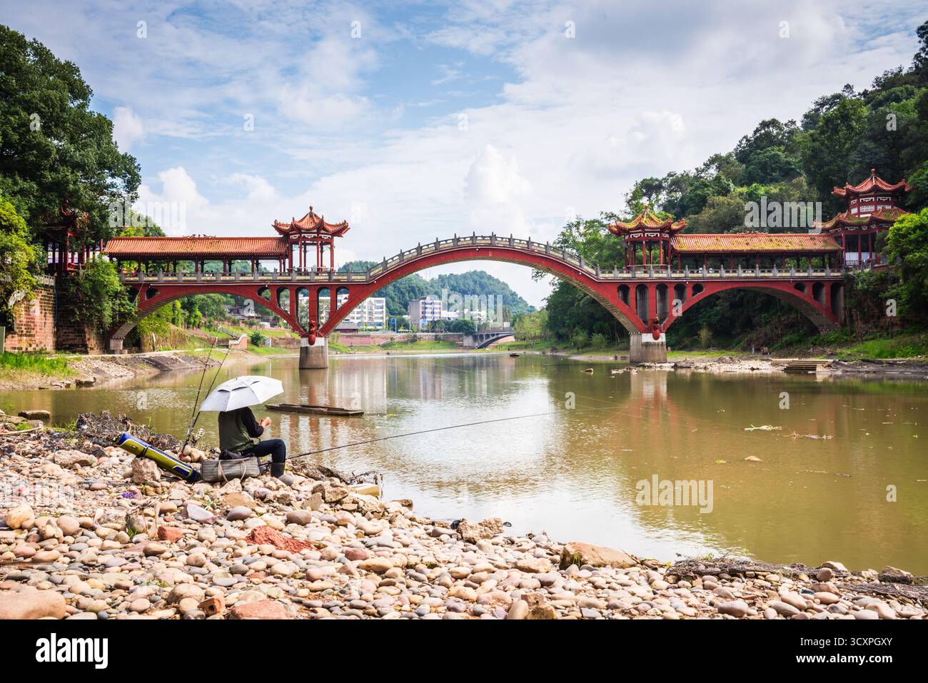 Leshan, Cina - 29 settembre 2018: Uomo che pesca sul fiume di fronte al ponte Leshan. Foto Stock