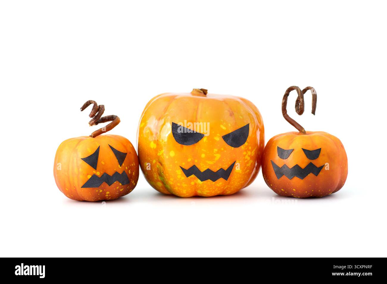 Simpatiche zucche di Halloween con facce di Jack-o'-lantern disposte in un gruppo giocoso su sfondo bianco Foto Stock