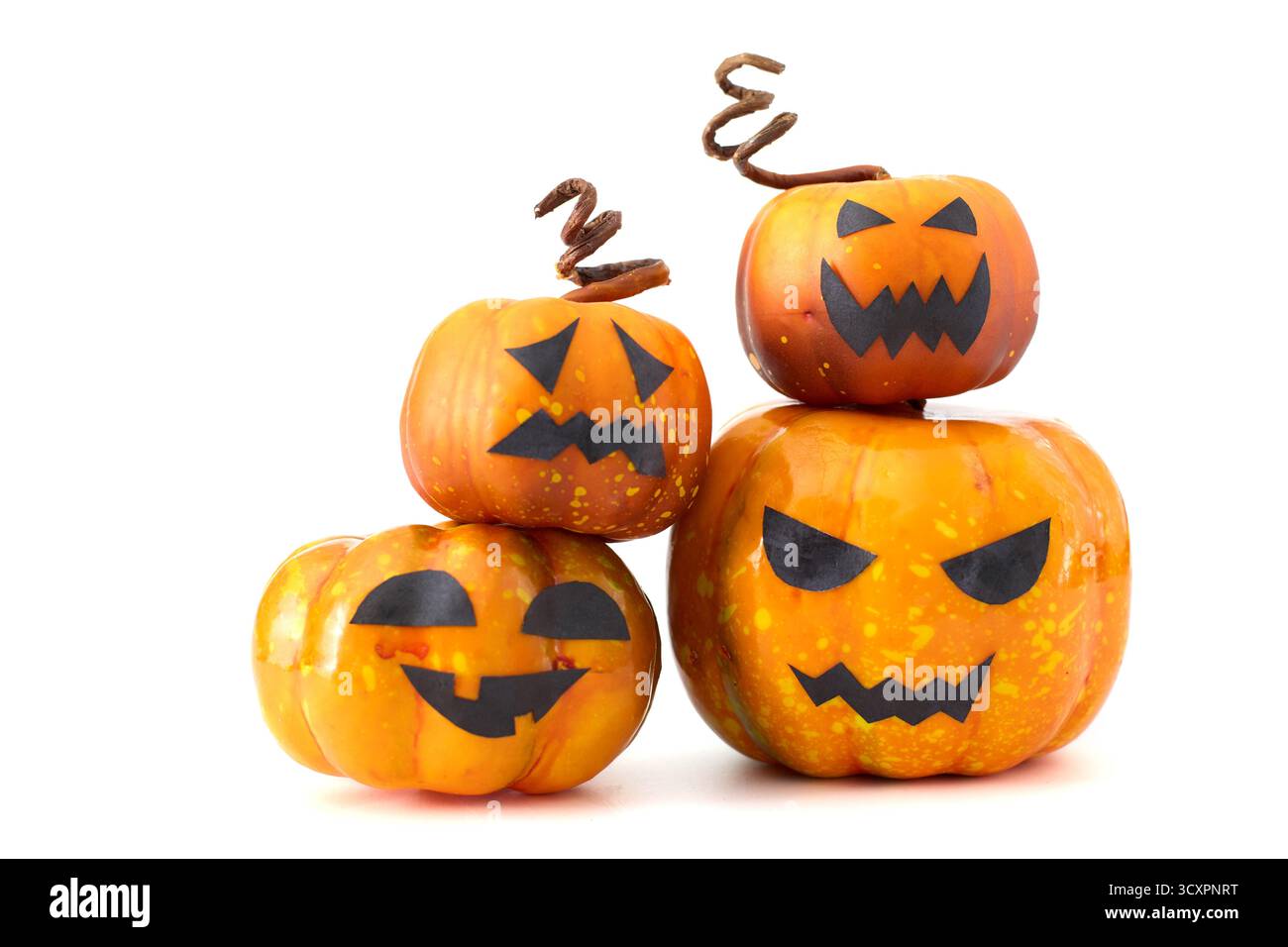 Simpatiche zucche di Halloween con facce di Jack-o'-lantern disposte in un gruppo giocoso su sfondo bianco Foto Stock