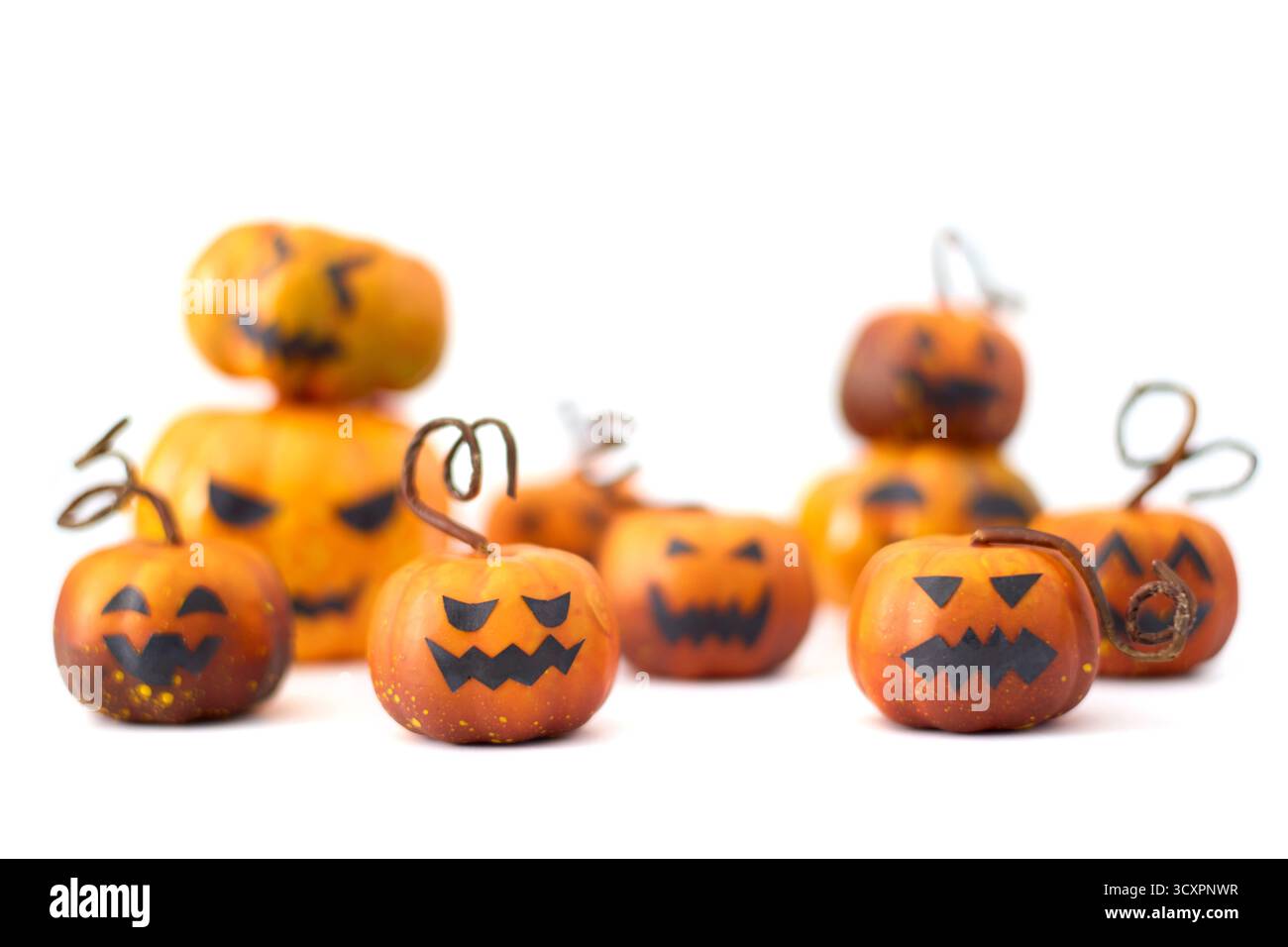 Simpatiche zucche di Halloween con facce di Jack-o'-lantern disposte in un gruppo giocoso su sfondo bianco Foto Stock