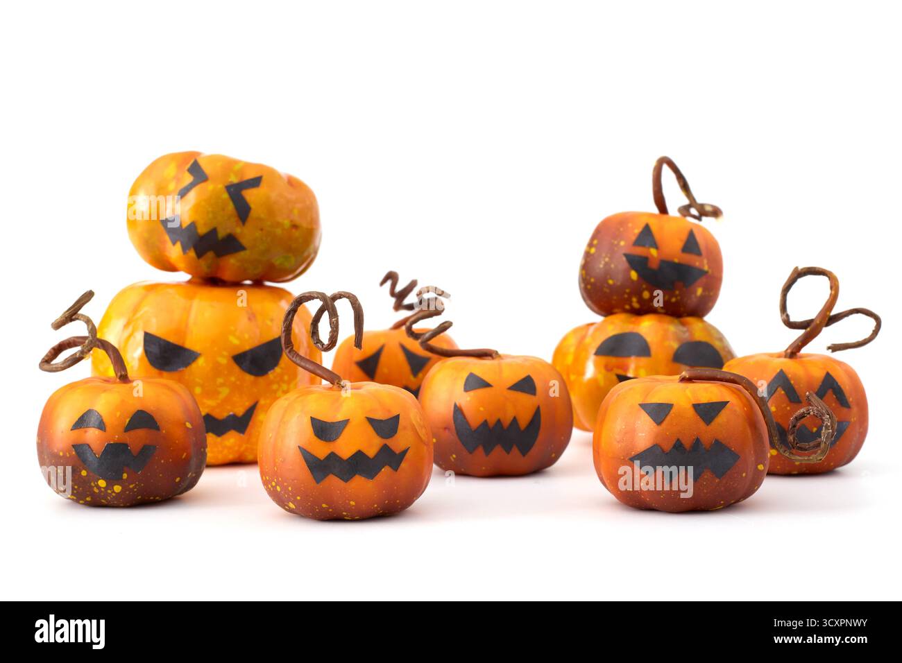Simpatiche zucche di Halloween con facce di Jack-o'-lantern disposte in un gruppo giocoso su sfondo bianco Foto Stock