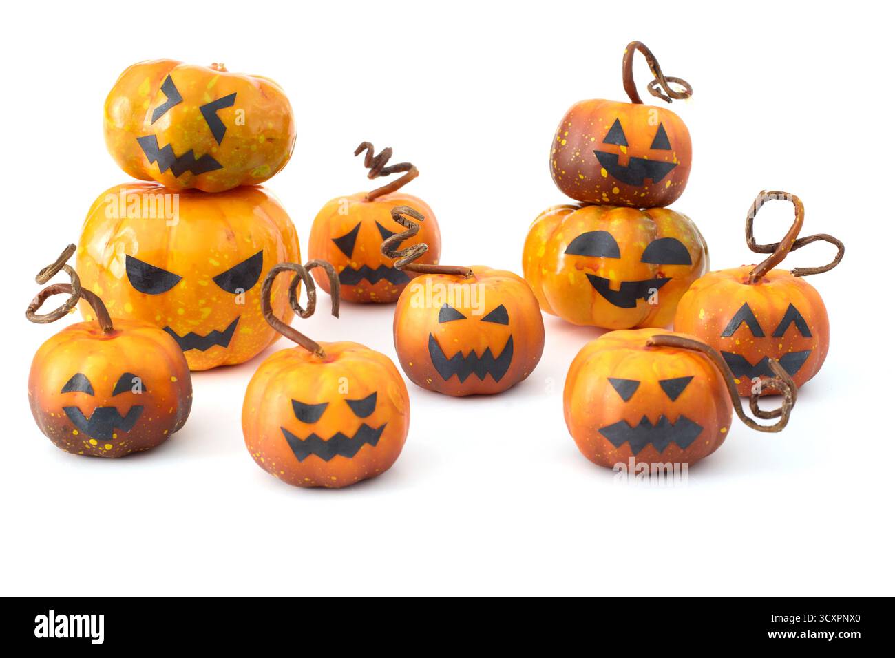 Simpatiche zucche di Halloween con facce di Jack-o'-lantern disposte in un gruppo giocoso su sfondo bianco Foto Stock