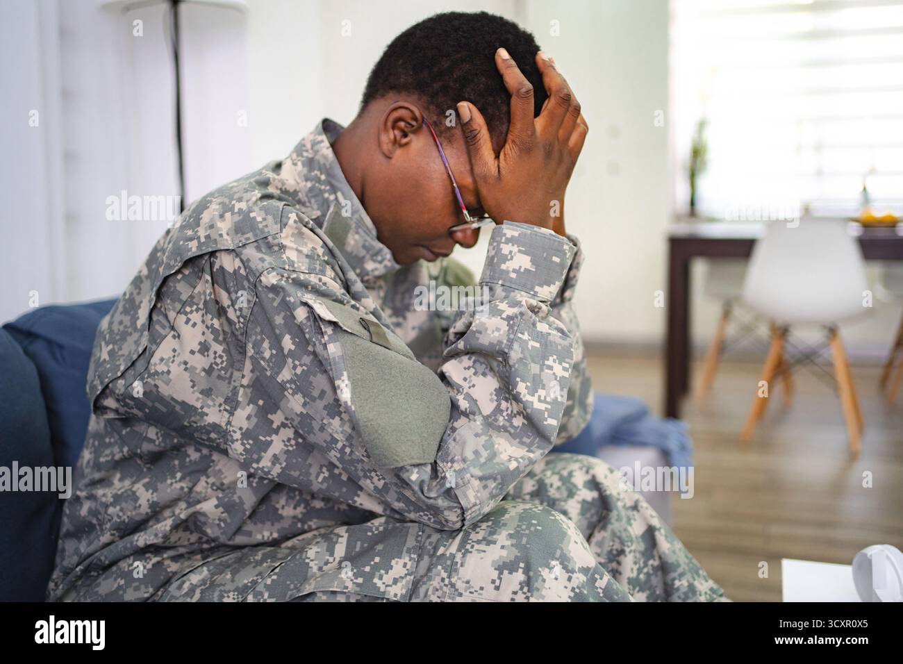 Soldato depresso affetto da stress post-traumatico seduto sul divano a casa Foto Stock