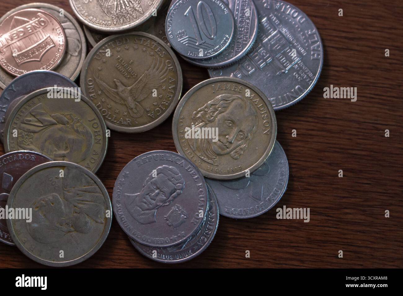 Primo piano di monete assortite degli Stati Uniti e dell'Ecuador, compresa la moneta commemorativa e standard su un tavolo di legno. Foto Stock
