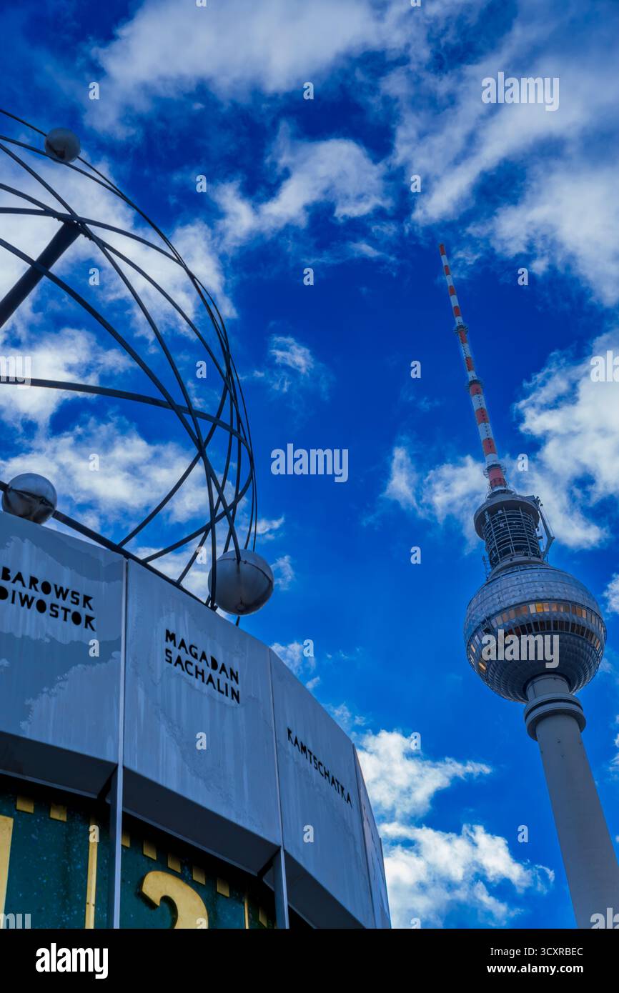 Orologio del mondo (Weltzeituhr) e torre della televisione (Fernsehturm) ad Alexanderplatz, Berlino: Due luoghi di interesse simbolici sotto un cielo estivo luminoso Foto Stock
