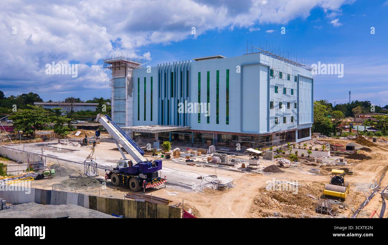 Vista aerea di un moderno centro commerciale in costruzione con pannelli di rivestimento metallici e attrezzature pesanti visibili Foto Stock