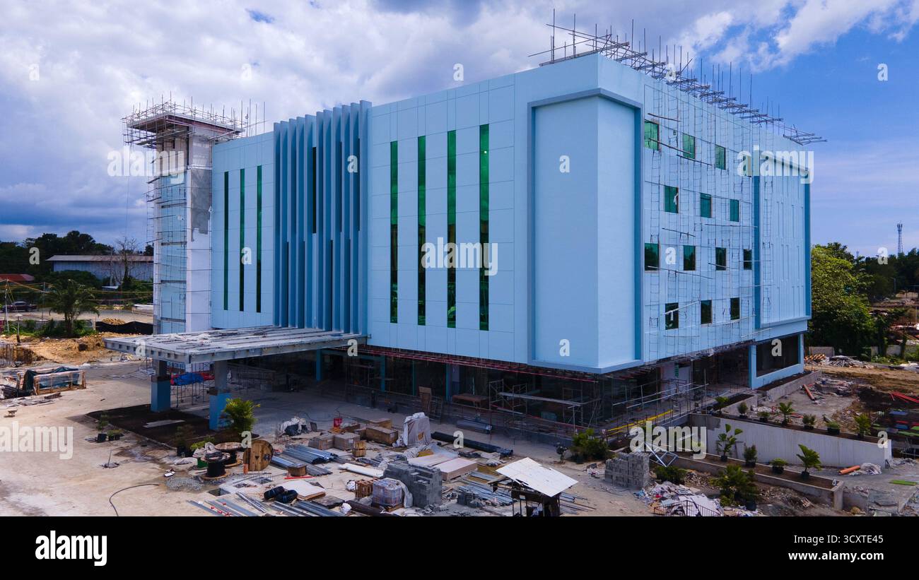 Vista aerea di un moderno centro commerciale in costruzione con pannelli di rivestimento metallici e attrezzature pesanti visibili Foto Stock
