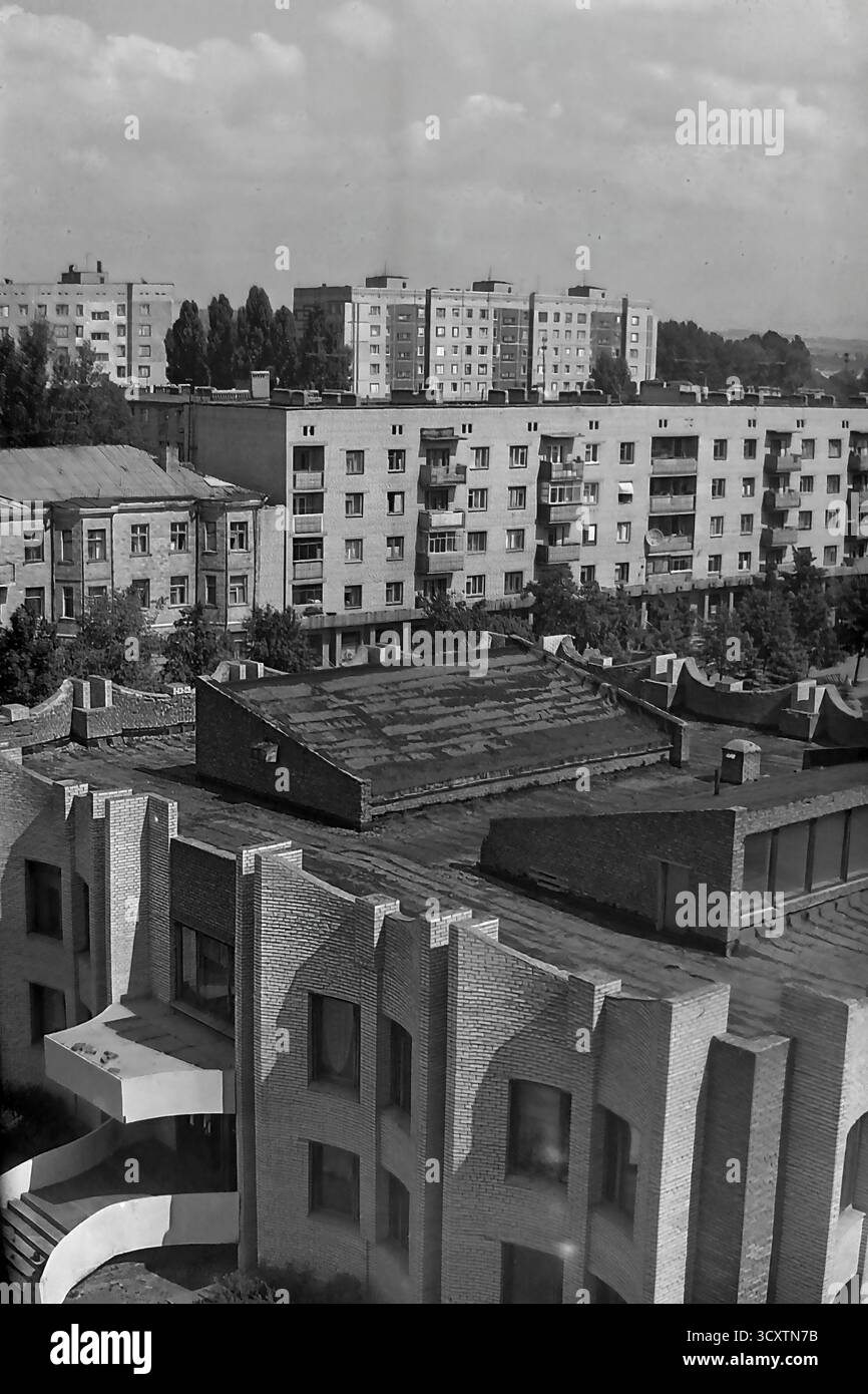 Una suggestiva foto d'archivio ad alto angolo degli anni '1980 cattura la texture urbana di Sloviansk, RSS Ucraina. La vista si affaccia sul caratteristico tetto modernista della Biblioteca centrale della città, situata in Piazza della Rivoluzione d'ottobre (ora Piazza Soborna). Oltre alla biblioteca, i tipici edifici residenziali di epoca sovietica sono lungo via Lenina (ora via Universytetska). Questa immagine mette in evidenza i contrasti architettonici dell'epoca ed è una preziosa testimonianza dell'ambiente urbano quotidiano di un tranquillo Donbas prima della guerra Foto Stock