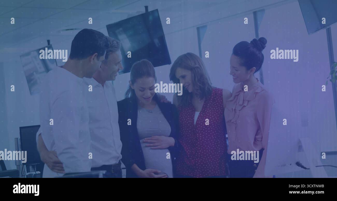 Riunire i colleghi intorno a una collega incinta, toccando la pancia vicino ai monitor in un ufficio aperto Foto Stock