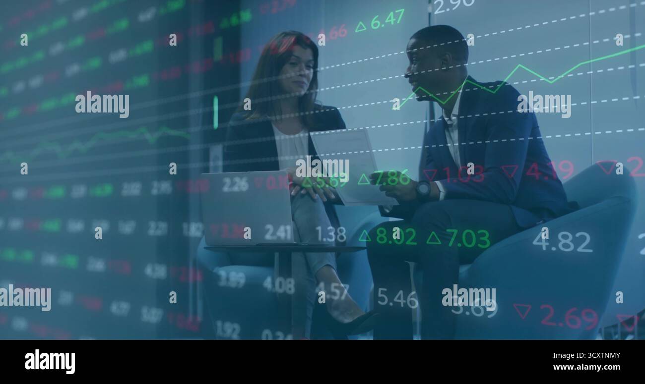 Discutere di colleghi adulti che esaminano le classifiche di mercato nella sala riunioni aziendale, con notebook e tablet Foto Stock