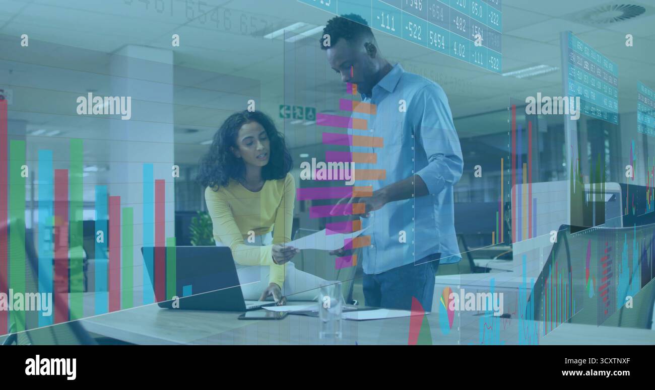 Colleghi pendenti in abiti da lavoro che esaminano i documenti stampati alla scrivania dell'ufficio, con laptop e penna Foto Stock