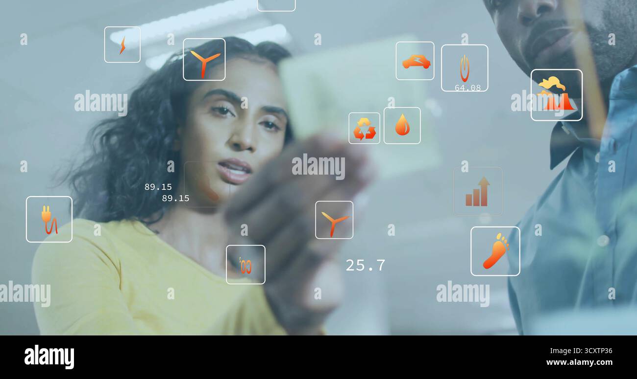 Collaborando con colleghi che tengono in mano appunti gialli e sovrappongono icone dietro un vetro in ufficio Foto Stock