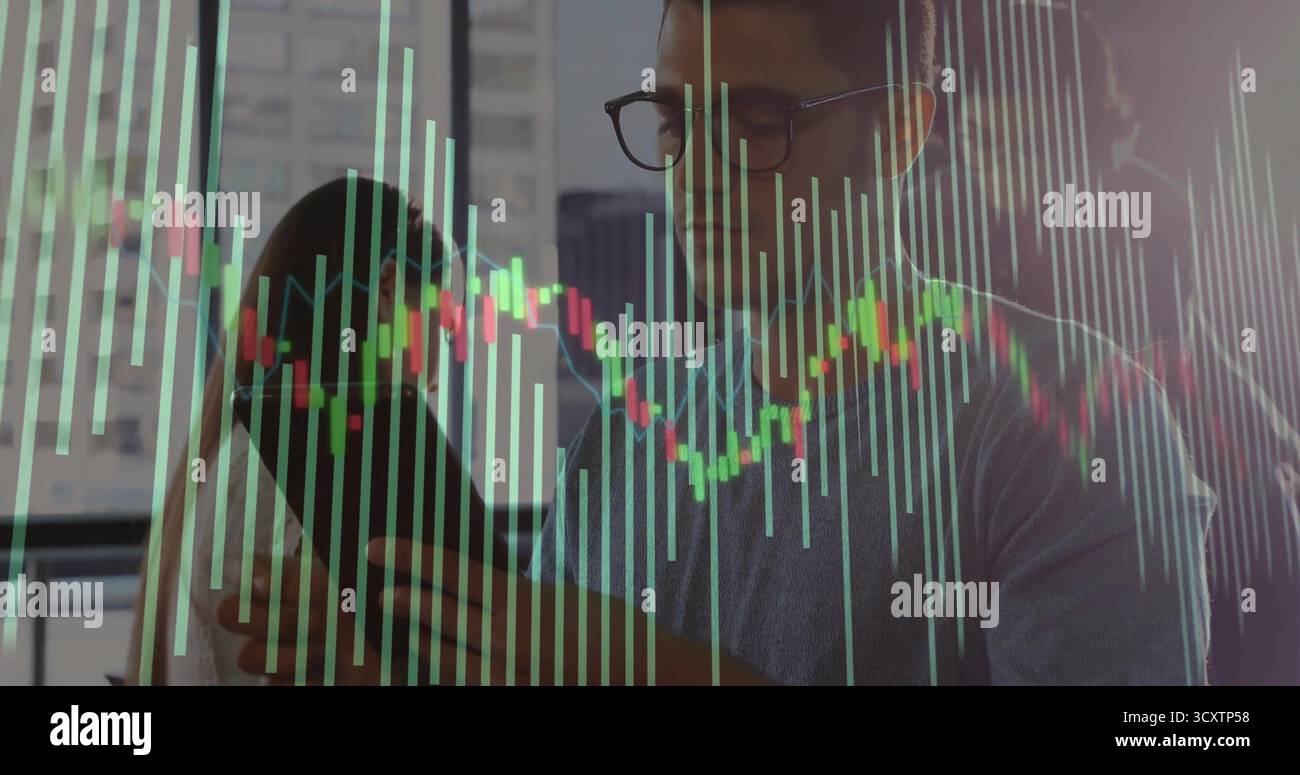 Tenendo in mano uno smartphone con un maglione analizzando le carte accanto alla finestra dell'ufficio sullo skyline, con un computer portatile Foto Stock