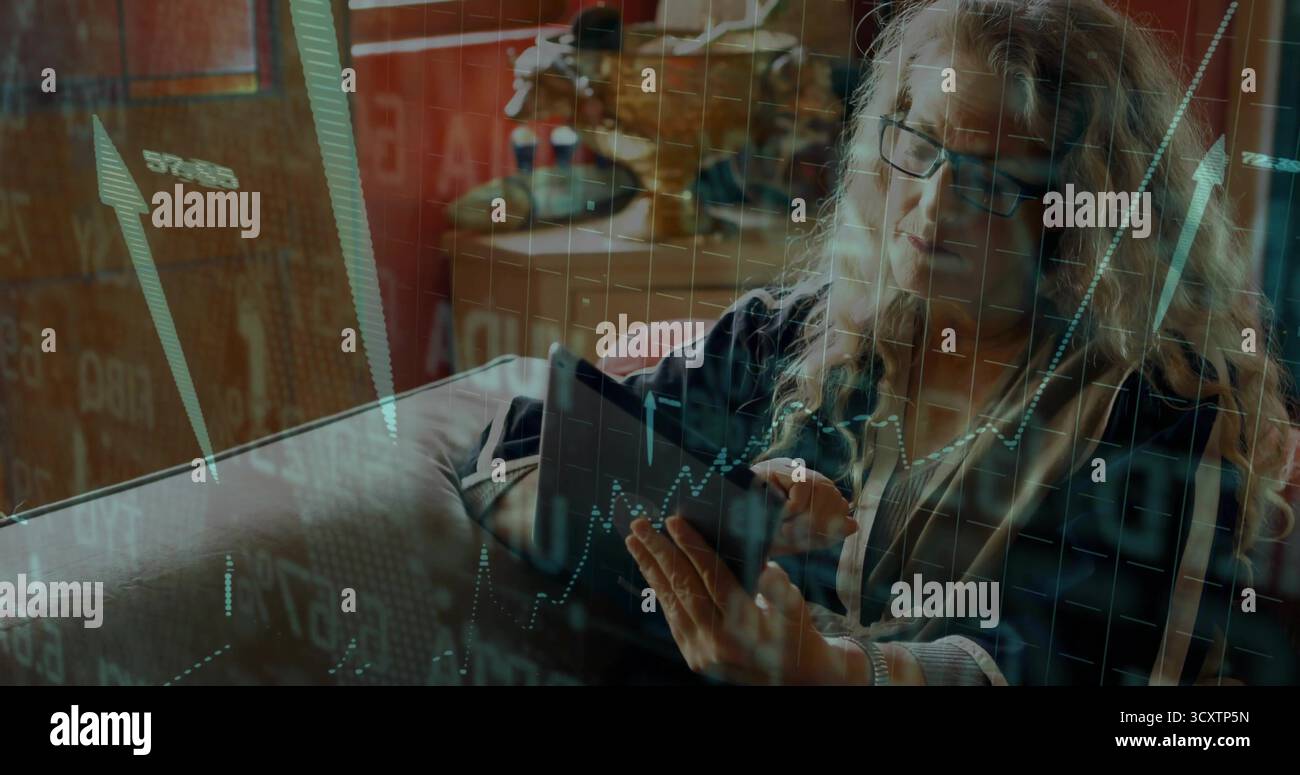 Analizzando gli investitori in maglione con zip che regge un tablet mostrando le carte sul divano a casa, la statuetta di bisonte Foto Stock