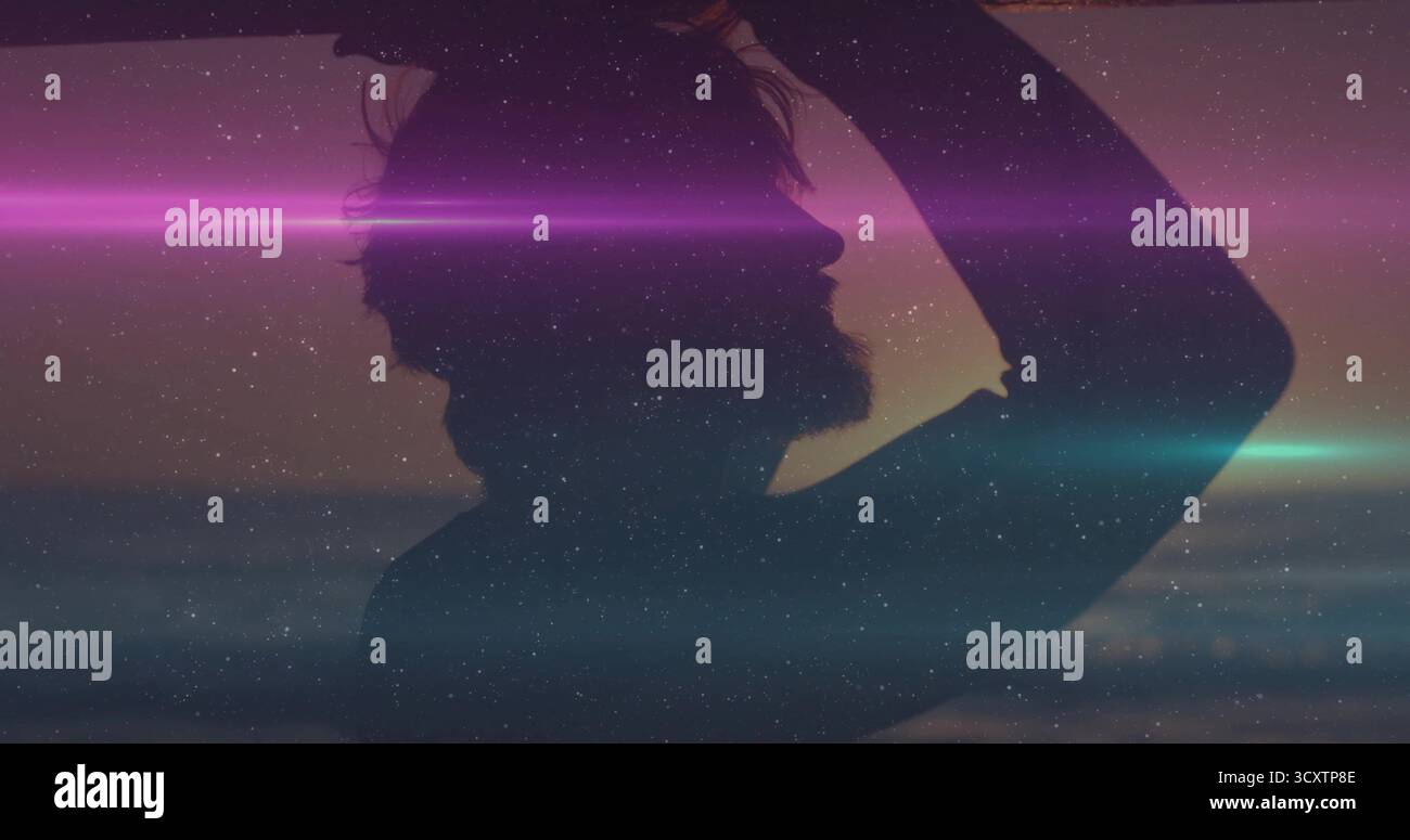 Silhouette in piedi uomo barbuto che solleva il braccio al mare calmo al crepuscolo mostrando lenti svasate, grana stellata Foto Stock