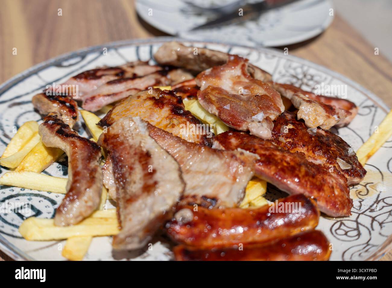 Grigliata mista di parrillada iberica con tagli di maiale, salsicce e chorizo su un piatto caldo, tradizionale piatto spagnolo barbecue dall'Andalusia, Spagna Foto Stock