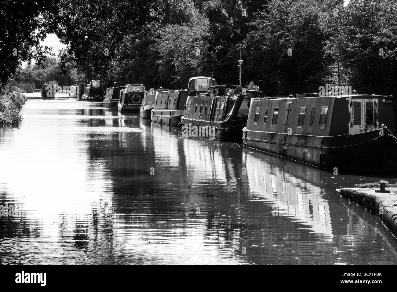 Le imbarcazioni per il Canale ormeggiavano lungo un tranquillo corso d'acqua in bianco e nero Foto Stock