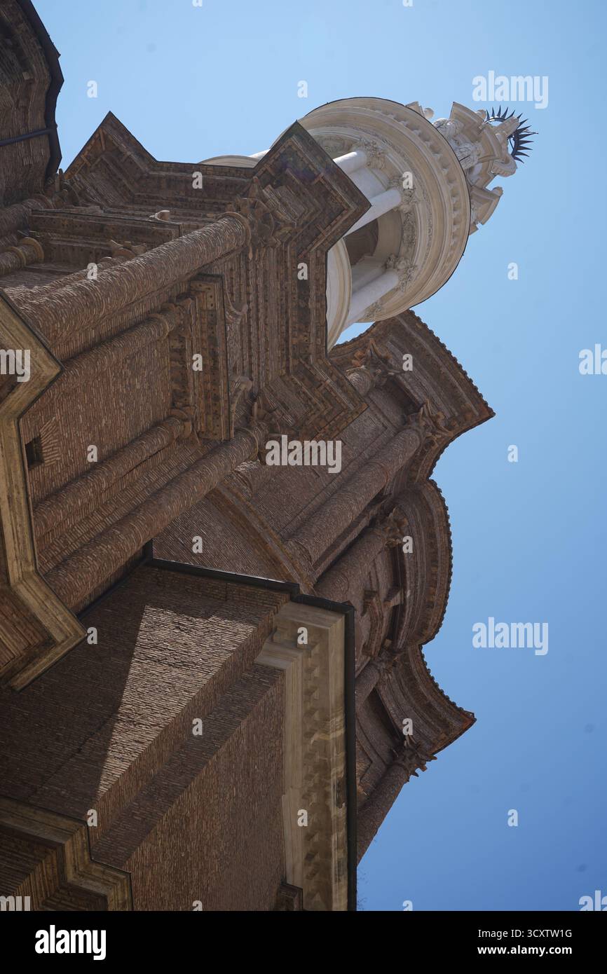 Una spettacolare vista a basso angolo di una storica chiesa in mattoni o facciata di un edificio a Roma, caratterizzata da intricati dettagli architettonici su un cielo azzurro. Foto Stock