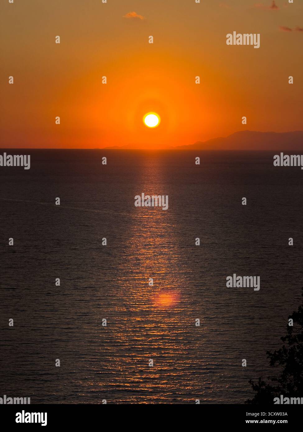 Tramonto dorato che si riflette sul mare con una piccola barca riflessa Foto Stock