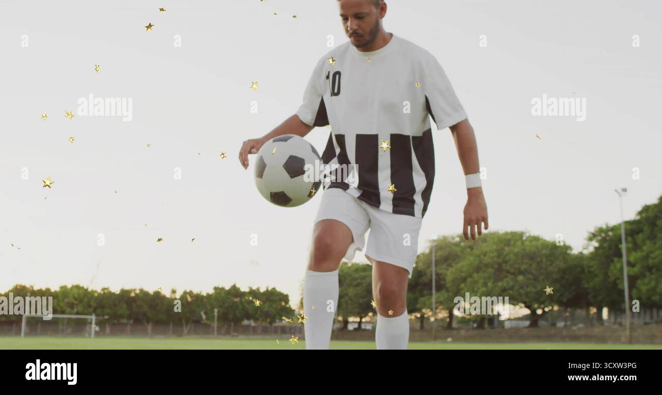 Giocatore di calcio in maglia a strisce e scarpe da calcio che giocheranno con palla nel parco, con pali di porta e pali leggeri Foto Stock