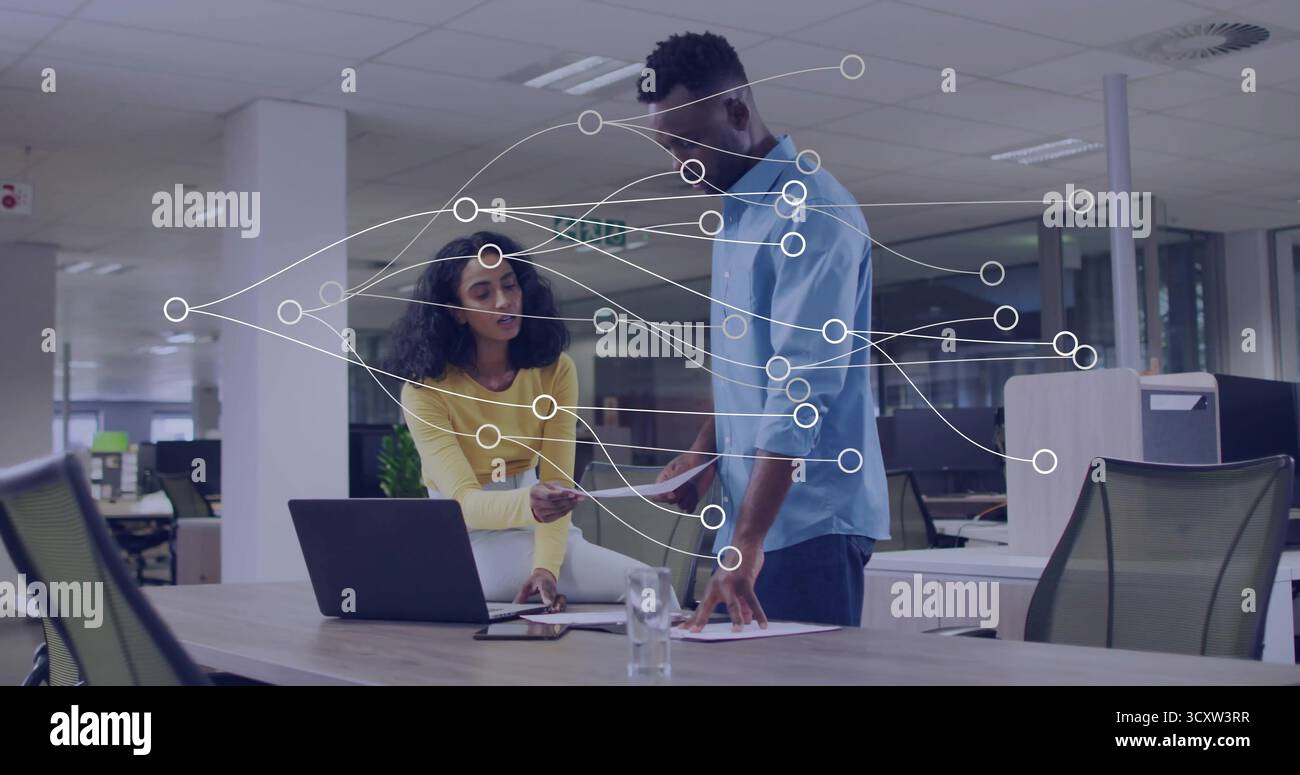 Revisione dei colleghi che discutono di documenti cartacei in un moderno ufficio open space, con notebook e notebook Foto Stock