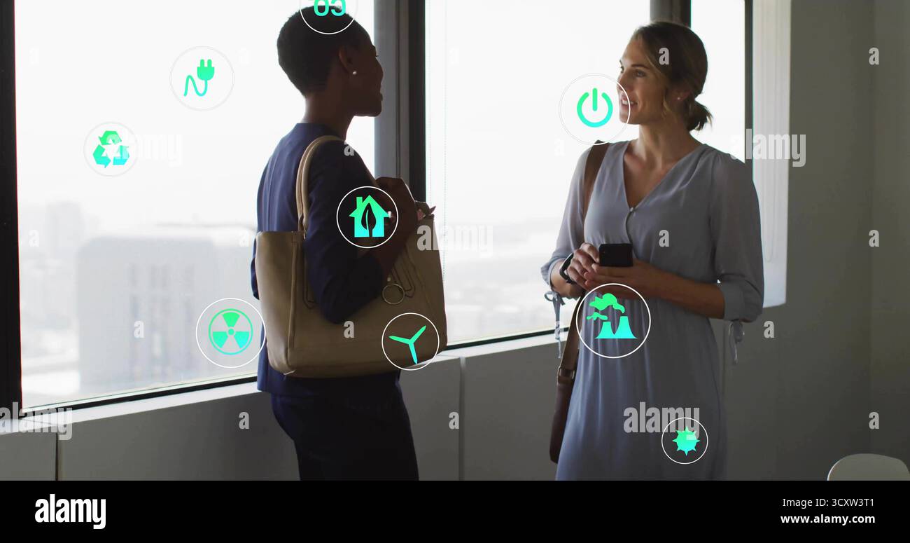 Due colleghi discutono di idee sulla sostenibilità nelle finestre degli uffici con smartphone e icone ecologiche Foto Stock