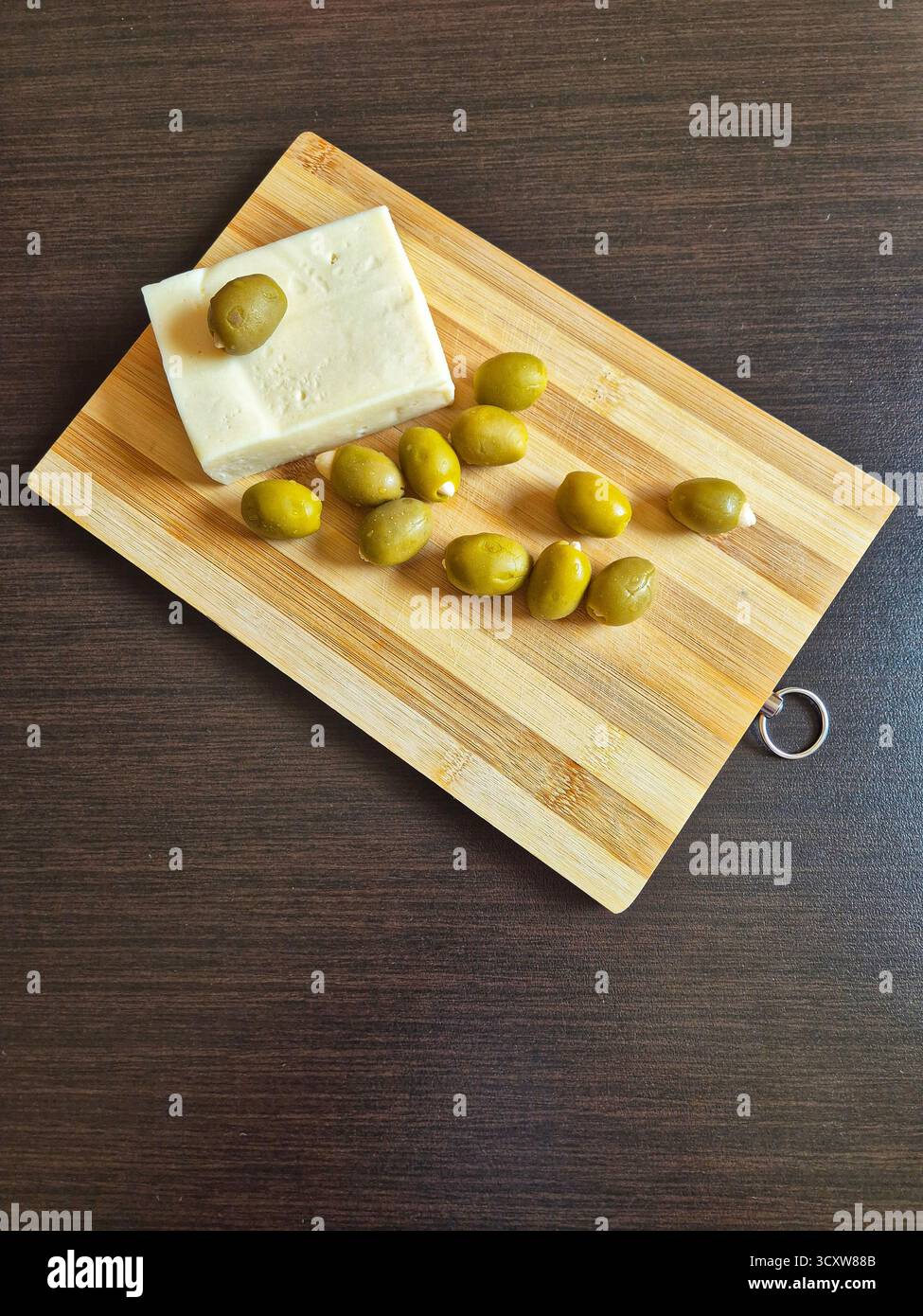 olive ricche e formaggio bianco salato (feta/brynza) su un tavolo di legno - Immagine stock catturata con smartphone