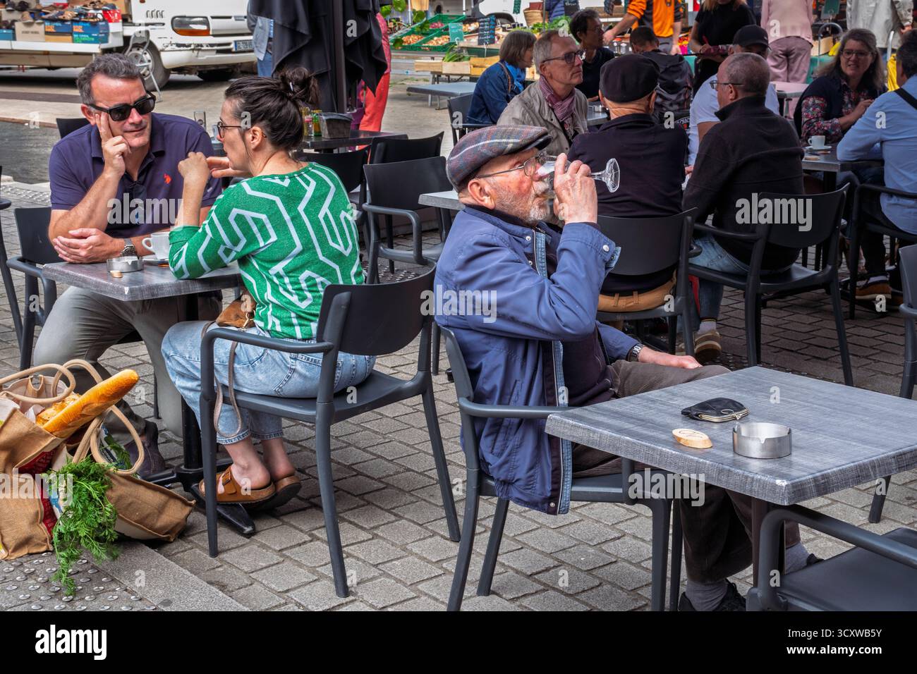 Un vecchio si gode un bicchiere di vino in un caffè marciapiede il giorno del mercato, Place du Centre, Guingamp, Bretagna, Francia Foto Stock