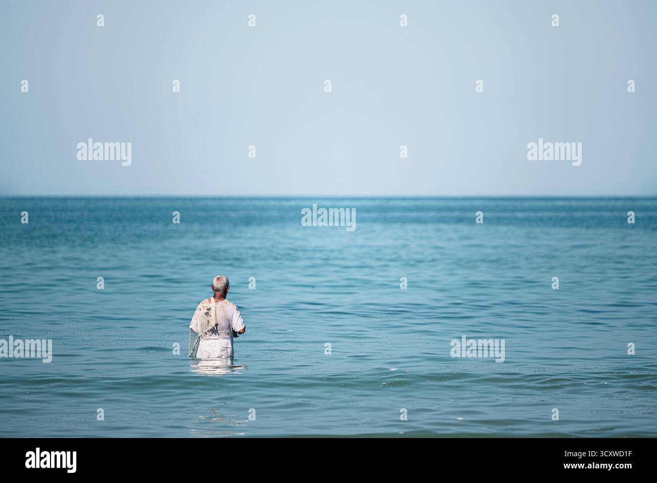 Un pescatore solitario attende nelle calme acque del Mar Arabico, praticando uno stile di vita tradizionale e senza tempo Foto Stock