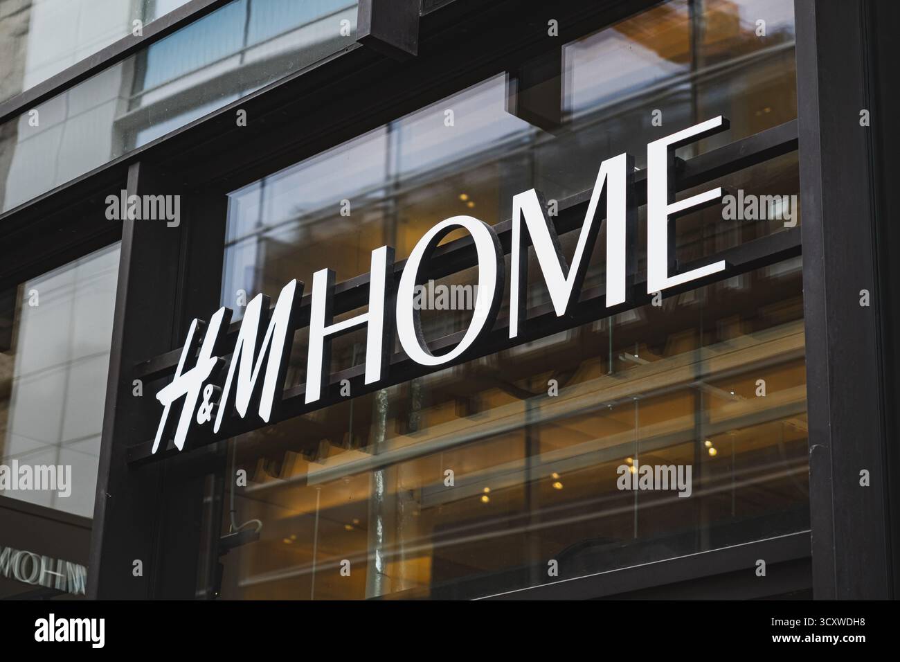 Il logo e le lettere del marchio H&M Home sono mostrati all'esterno di un moderno centro commerciale Foto Stock