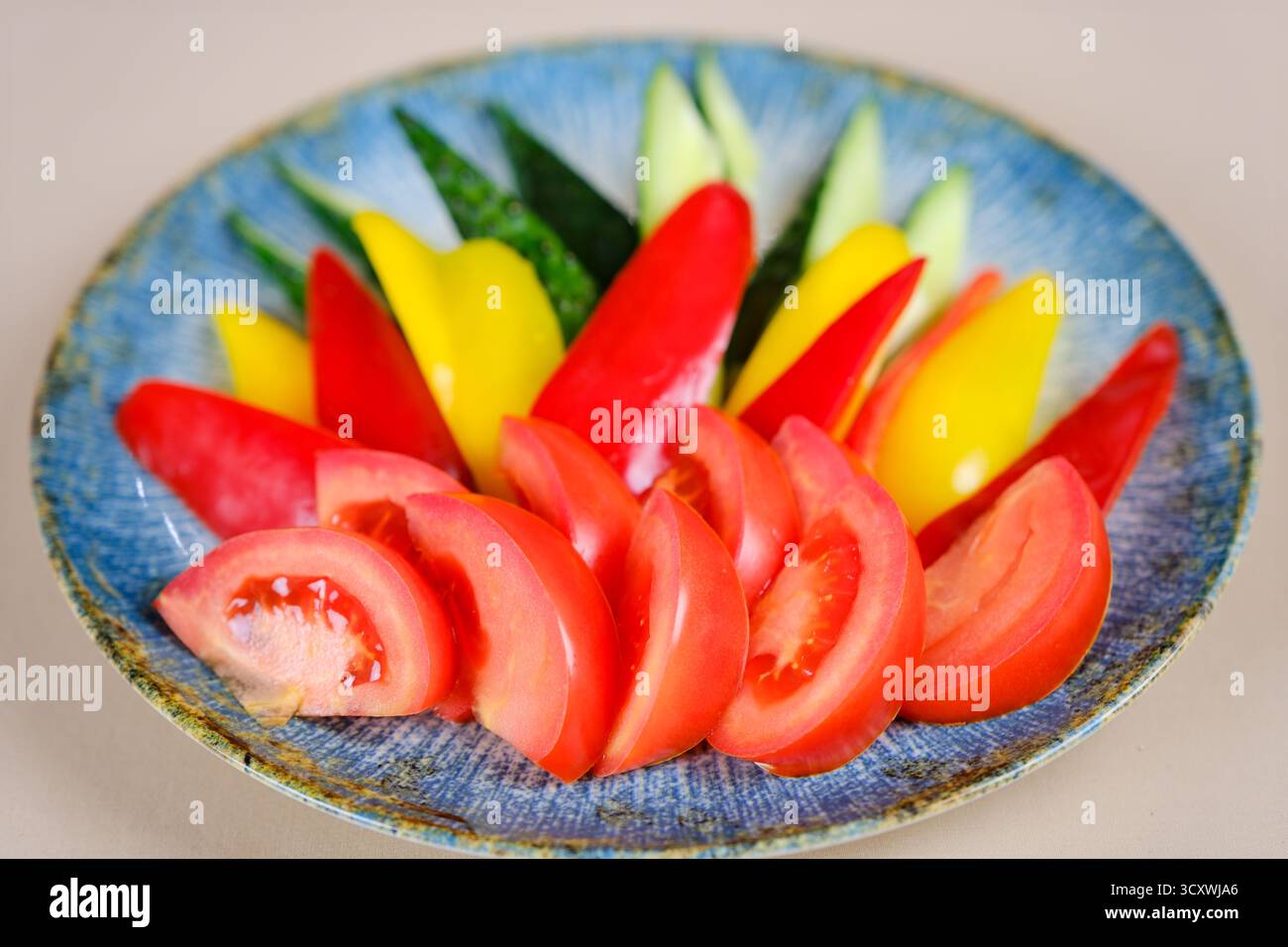 pepe, pomodoro, cetriolo in pezzi su un piatto di verdure, brocca di olio, recipiente con verdure, coltello e forchetta sul tavolo. Foto di alta qualità Foto Stock