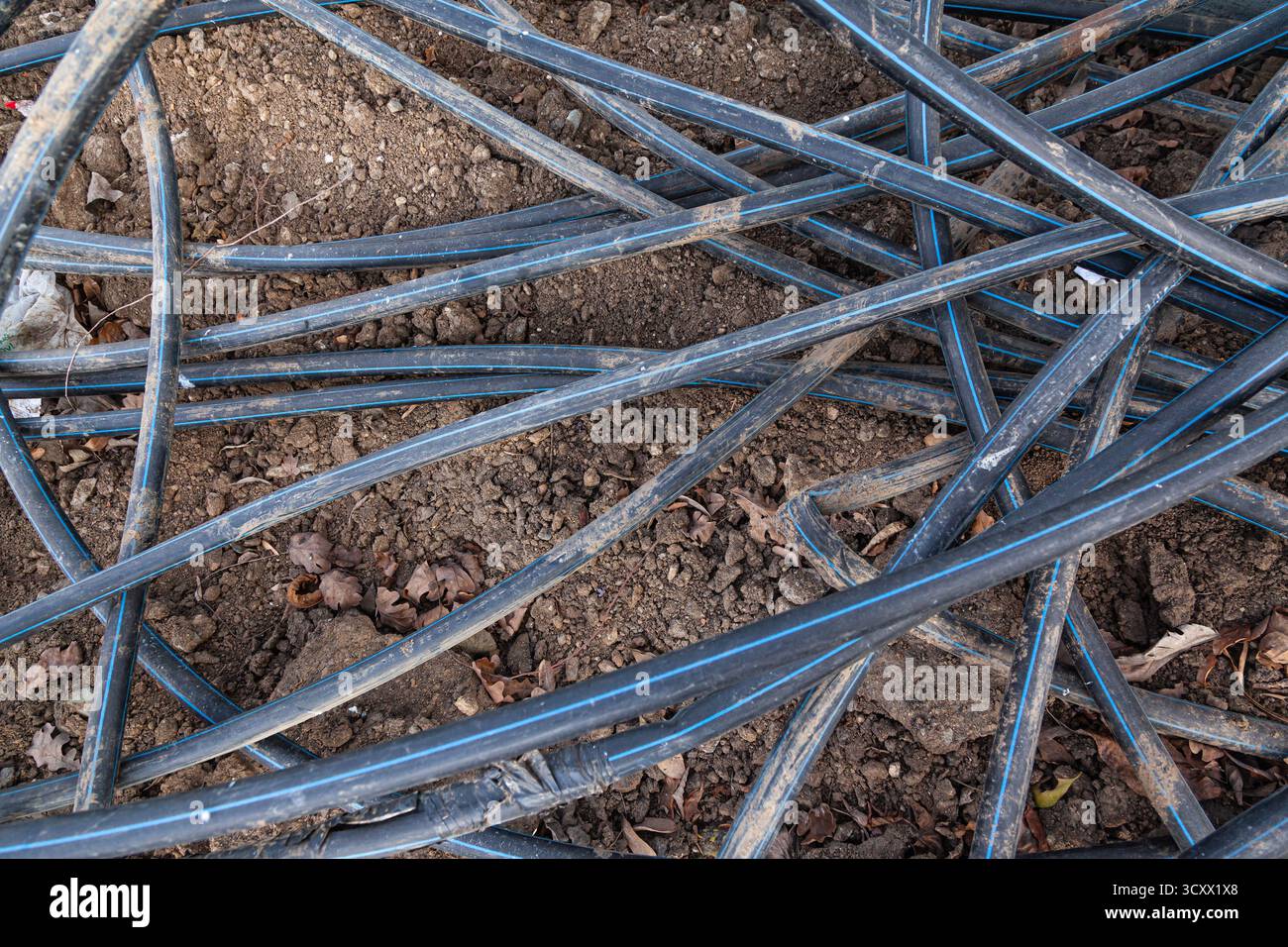 Pile di tubi flessibili in plastica dura nera a terra Foto Stock